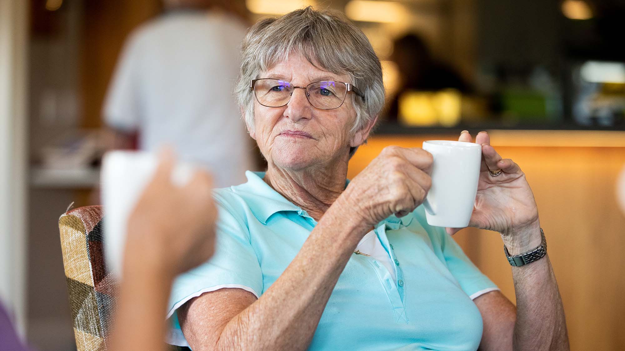 An older woman sitting on the ground holding her head