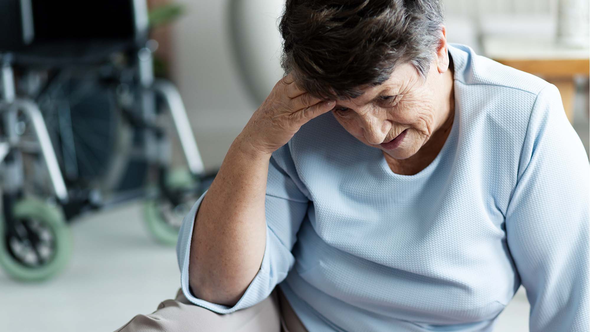 An older woman sitting on the ground holding her head