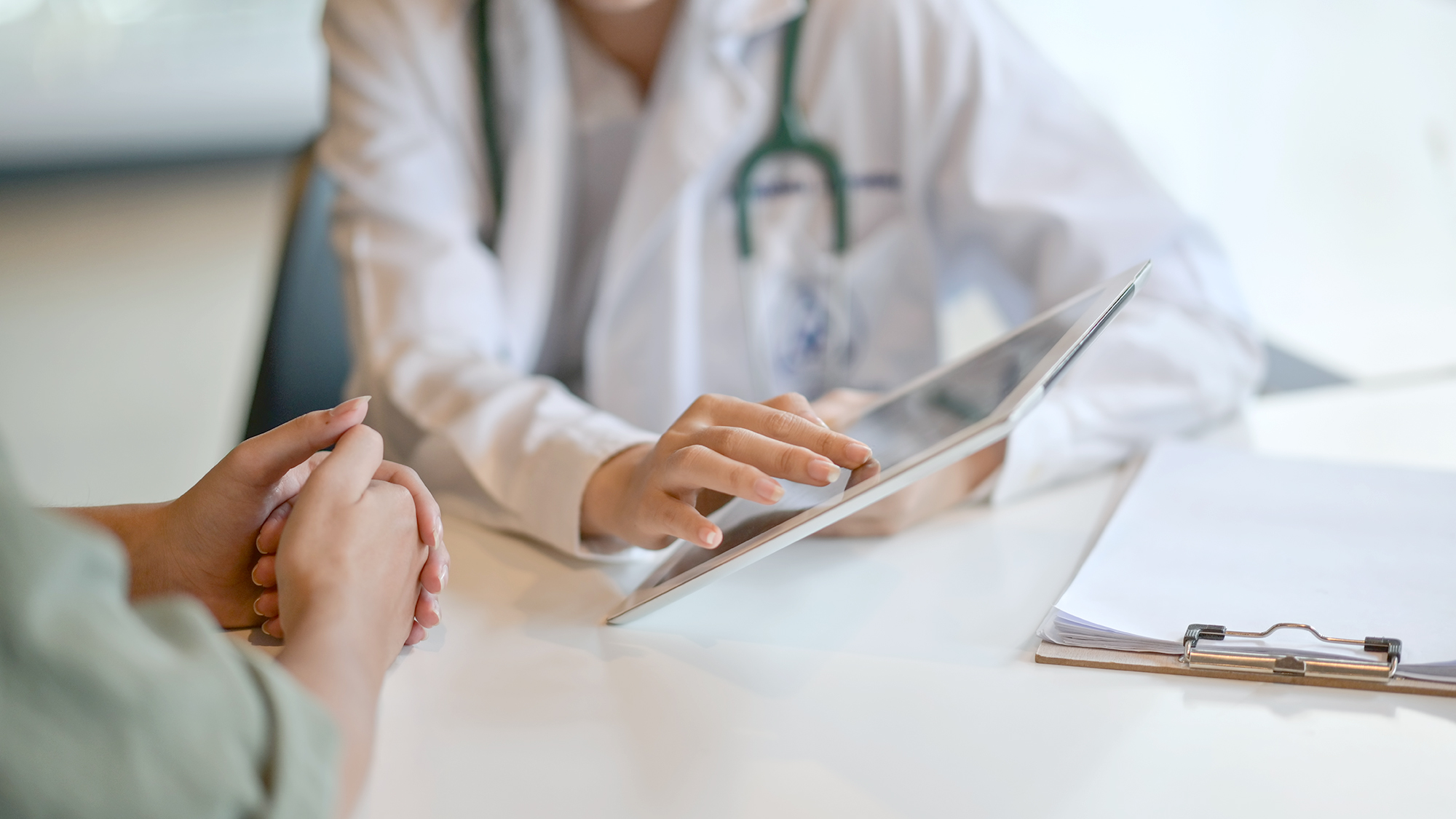 An older man talking to a woman doctor and looking at a chart