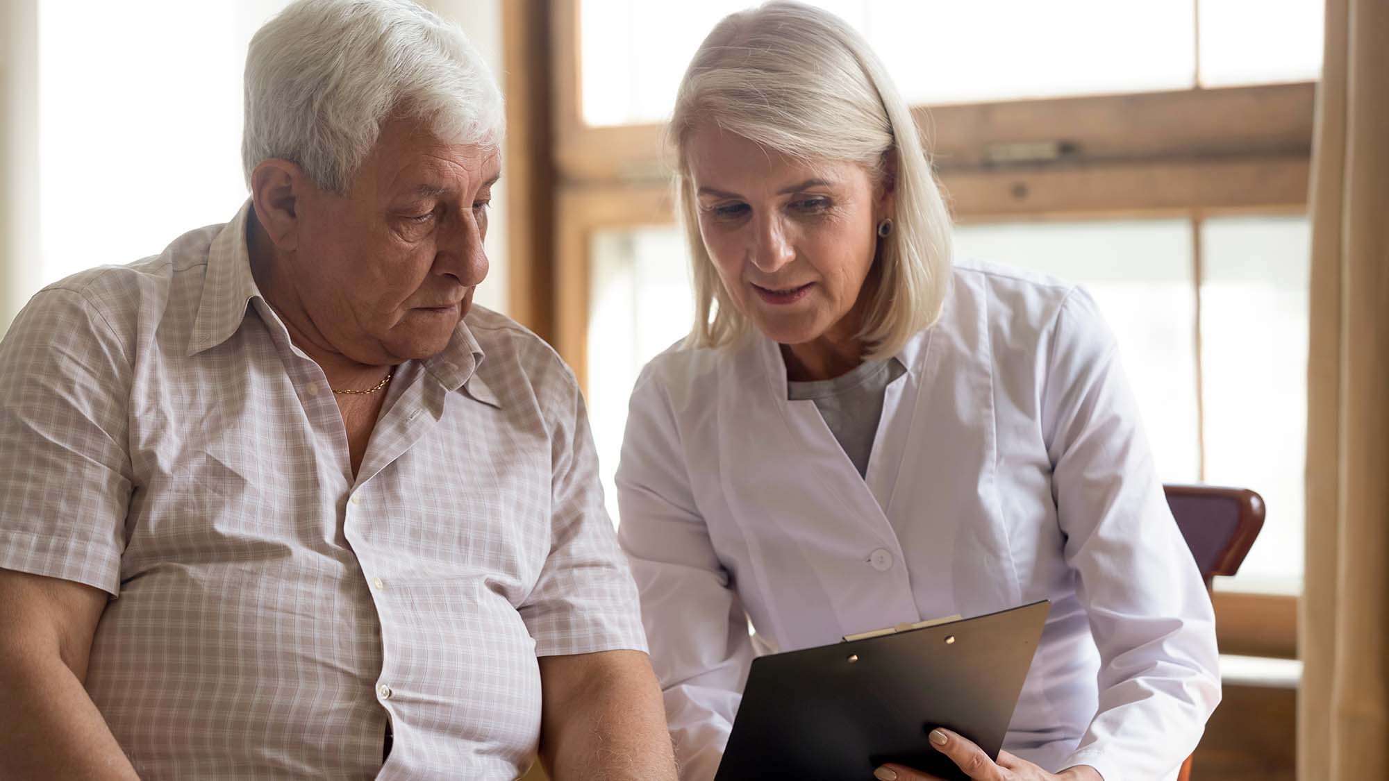 An older man talking to a woman doctor and looking at a chart