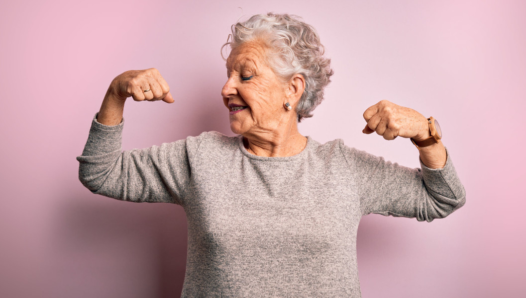 An older woman smiling and flexing her muscles